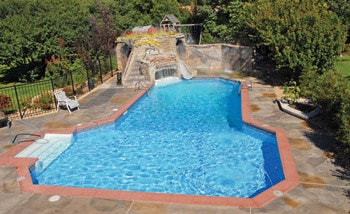 When the cave and waterfall were added in 2005, the job did not include upgrading the concrete deck. It was plain gray butting up to conventional aluminum coping. To dress it up a bit after the fact, the homeowners opted for a thin stamped-concrete overlay, which was a slight improvement but still not quite what they wanted.