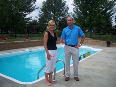 photo of Cathy Frey and Mark Gramza with $1,000 gas card in front of a swimming pool