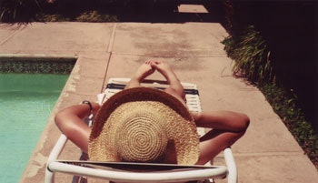 photo of lady with a hat lounging by a pool