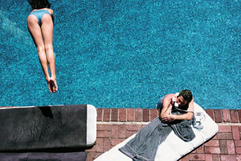 photo of girl diving and man on phone in pool