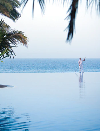 photo of a man cleaning an outdoor pool