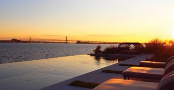 Throgs Neck Bridge and bay at sunset with vanishing edge pool by Paco Pools and Spas in foreground