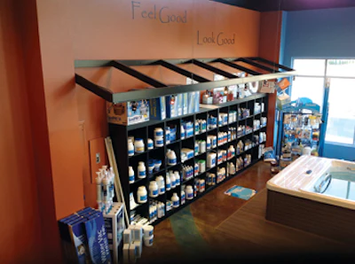 Aqua and sienna colors on the wall add visual interest and tie into the brand's color story. Shelves against a back wall are stocked, but not stuffed with product — and leaving spaces between gives product a more boutique feel.