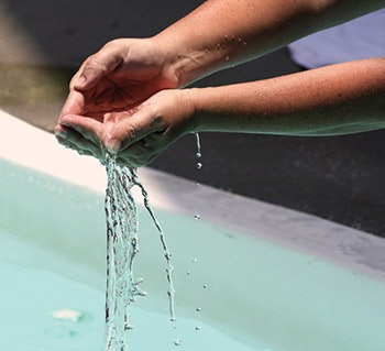photo of person letting swimming pool water run through their hands