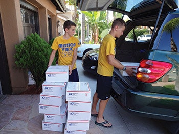 photo of children loading boxes of goggles into a van
