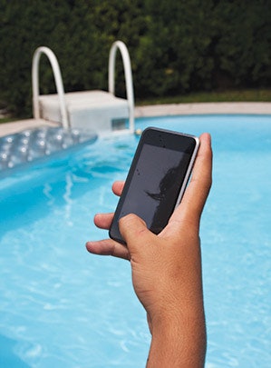 photo of someone holding an iphone by a pool