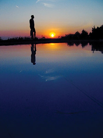 photo of a man by a pond at sunset