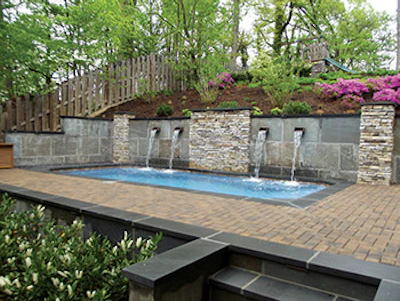 The water features, broad deck area and landscape lighting help create an inviting space that harmonizes with the setting.