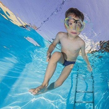 photo of a boy in a swimming pool wearing goggles