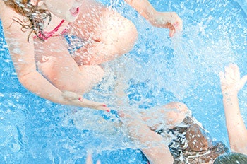 photo of two children splashing in a pool