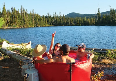 photo of people in a backcountry hot tub by a lake
