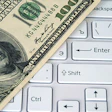 photo of a hundred dollar bill placed on a computer keyboard