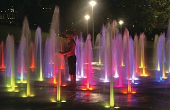 photo of a boy playing in colorful fountains
