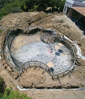 After nearly two years of frustration securing necessary building permits and Coastal Commission approvals, we were finally able to get down to the work of building the pool. Here we can see how the subtle aesthetic design of the pool betrays the massive concrete substructure needed to reach bedrock.