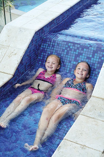 Two young girls enjoy a comfortable soak in a custom water feature.