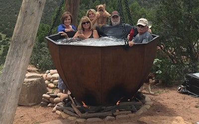 The hot tub is indeed anchored to a concrete foundation, but the wooden beams and chains help turn this hot tub into a backyard focal point.