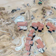 Aerial view of pool and lagoon construction. Note the depots of supplies stacked in the sand, including palm trees and pipe, along with active heavy hydraulic equipment (material handler, backhoe and wheel dozer).