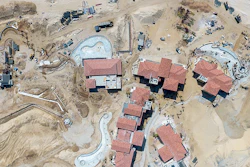 Aerial view of pool and lagoon construction. Note the depots of supplies stacked in the sand, including palm trees and pipe, along with active heavy hydraulic equipment (material handler, backhoe and wheel dozer).