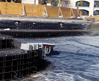 As depicted in this photo, the pool was built using reinforced concrete walls lined with PVC that were then covered with a layer of shotcrete to protect the vinyl (far right). MAXA also built a berm around the pool to help fight invading sand.