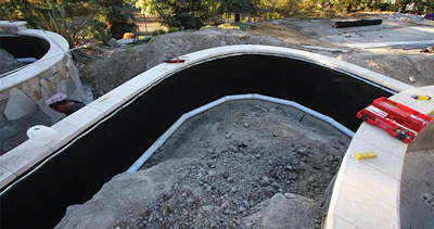 The French drain plumbing has been installed with a multi-flow drainage composite material from MiraDRAIN that aids in the disbursal of water away from the retaining wall into the drainage system.
