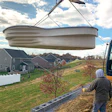 The crew at Bob’s Pools creeps toward a waiting hole with a fiberglass pool suspended from a Case excavator with a grappling attachment. The company works with other installers in the area to cut per-unit costs for pool delivery. (Photo courtesy Bob’s Pools)