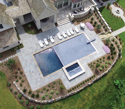 Matching automatic covers on the pool and spa powerfully integrate the geometry of this magnificent backyard aquatic scene built by Keesling Custom Pools, Patio & Construction, Indianapolis, Ind. The custom gunite 24-by-54-foot pool and 8-by-12-foot spa are finished in ‘Maui Midnight’ (from Hydrazzo), a rich colored surface that adds depth and shimmers nicely in the sun. Indiana limestone provides a suitable frame for this work of art. (Photo courtesy Automatic Pool Covers)