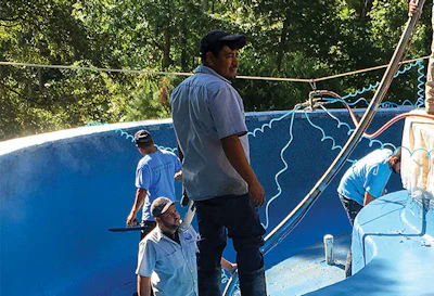 Application of the pool finish is a team effort. Here, a central manifold feeds five sprayers for rapid coverage. Photo courtesy J&M Pools.