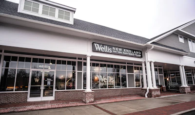Wellis New England is part of a strip mall that was built prior to the pandemic. The clean brick pillar foundations and glass frame walls give the facade warmth and charm.