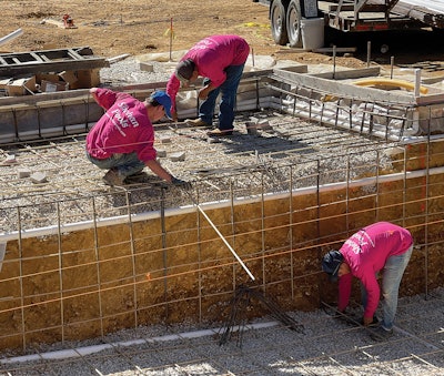 El equipo de Shehan Pools coloca y ata barras de refuerzo, utilizando procedimientos estándar para atar.  Tenga en cuenta el uso de barras de refuerzo de acero para transiciones y curvas de 90 grados, mientras que los tramos largos de barras de refuerzo rectas son de fibra de vidrio.  