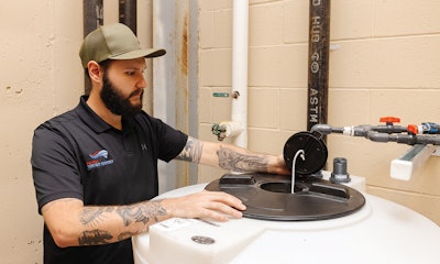 Patriot Water Works Install Technician Thomas Soukup checks chlorine tank level to determine the chlorine delivery schedule.
