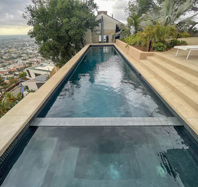 The dark interior surface creates an inviting reflective surface, while the soft-colored concrete and clean lines harmonize with the home's contemporary architecture.