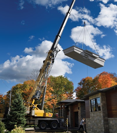 The means of getting the shell to the excavated hole varies according to the architecture and landscape of the home. Here, a rented mobile crane is snugged up within a few feet of the garage door.