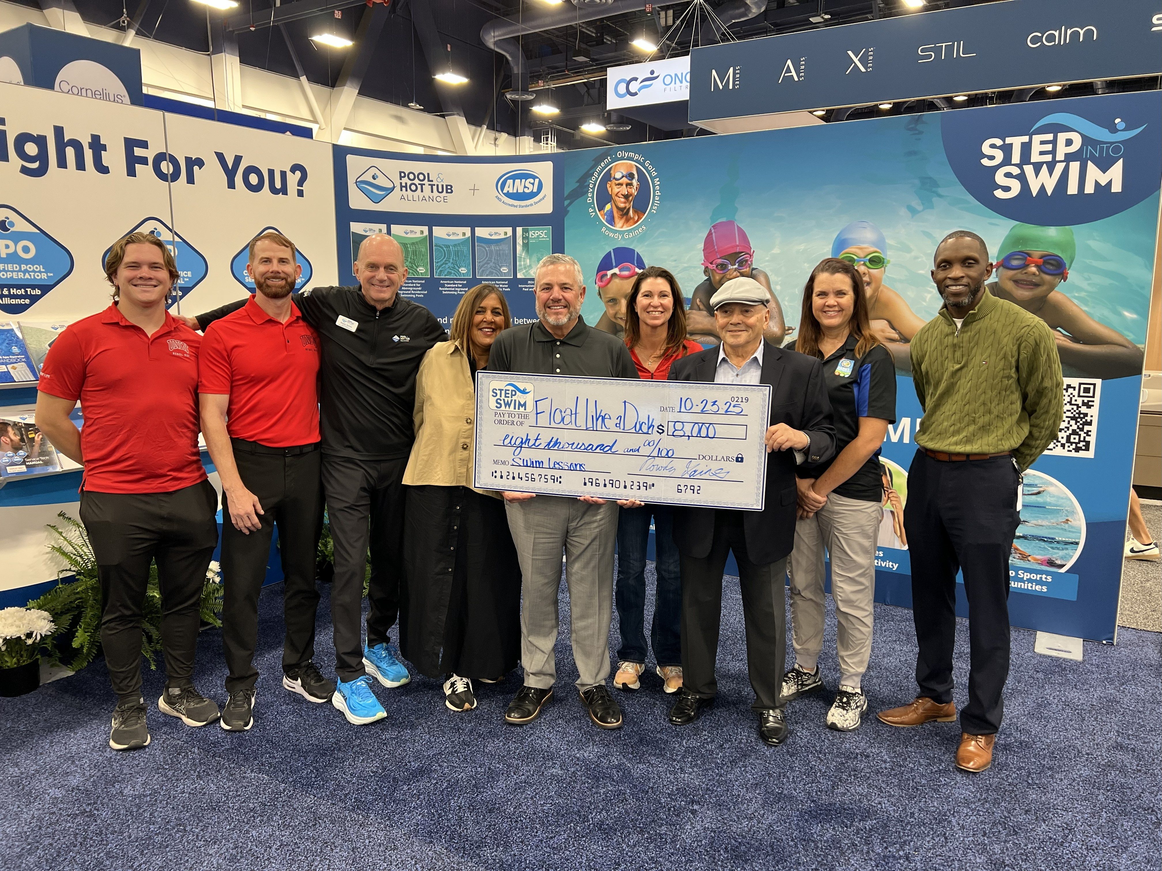 Group of professionals posing with large check at Step Into Swim event booth