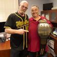 Two colleagues posing together with a professional wrestling championship belt