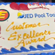 Celebration cake with JED Pool Tools Customer Excellence Award and logos