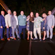 Group of eight professionals posing together at an evening event