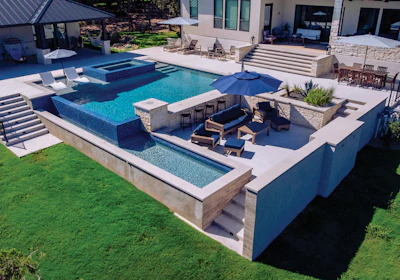 Luxury backyard with resort-style swimming pool, spa, lounge seating, and modern home exterior