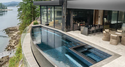 Modern waterfront home with infinity pool overlooking calm lake and forested shoreline