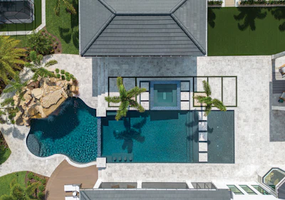 Aerial view of modern luxury home with curved swimming pool, patio, and manicured landscaping