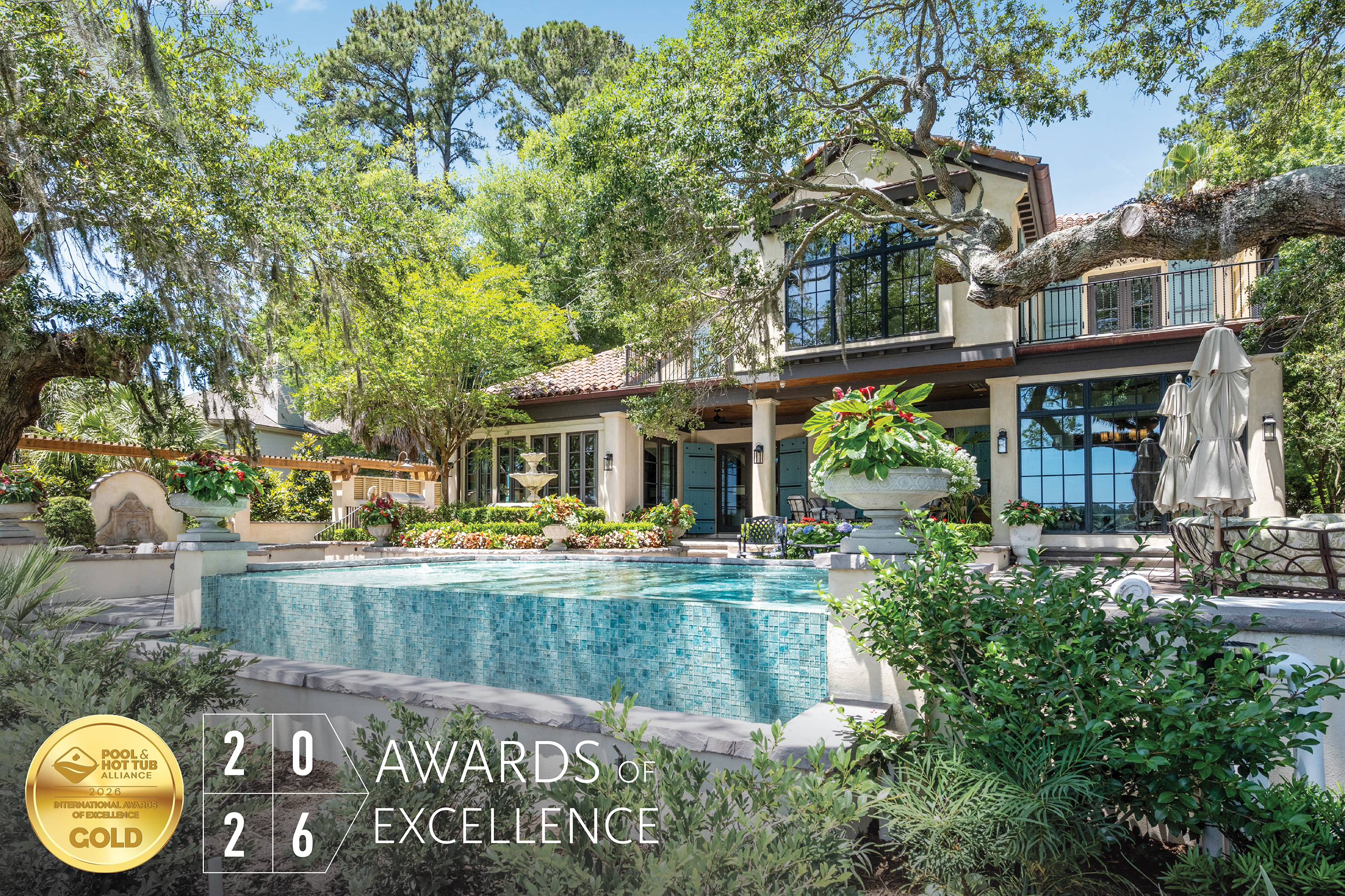 Luxury modern home with turquoise pool surrounded by mature trees and manicured landscaping, featuring 2026 Awards of Excellence gold badge