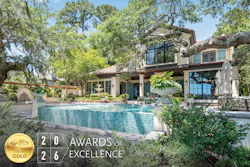 Luxury modern home with turquoise pool surrounded by mature trees and manicured landscaping, featuring 2026 Awards of Excellence gold badge