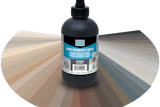 Black grout colorant and sealer bottle with Laticrete label displayed against a color swatch fan showing neutral and gray tones