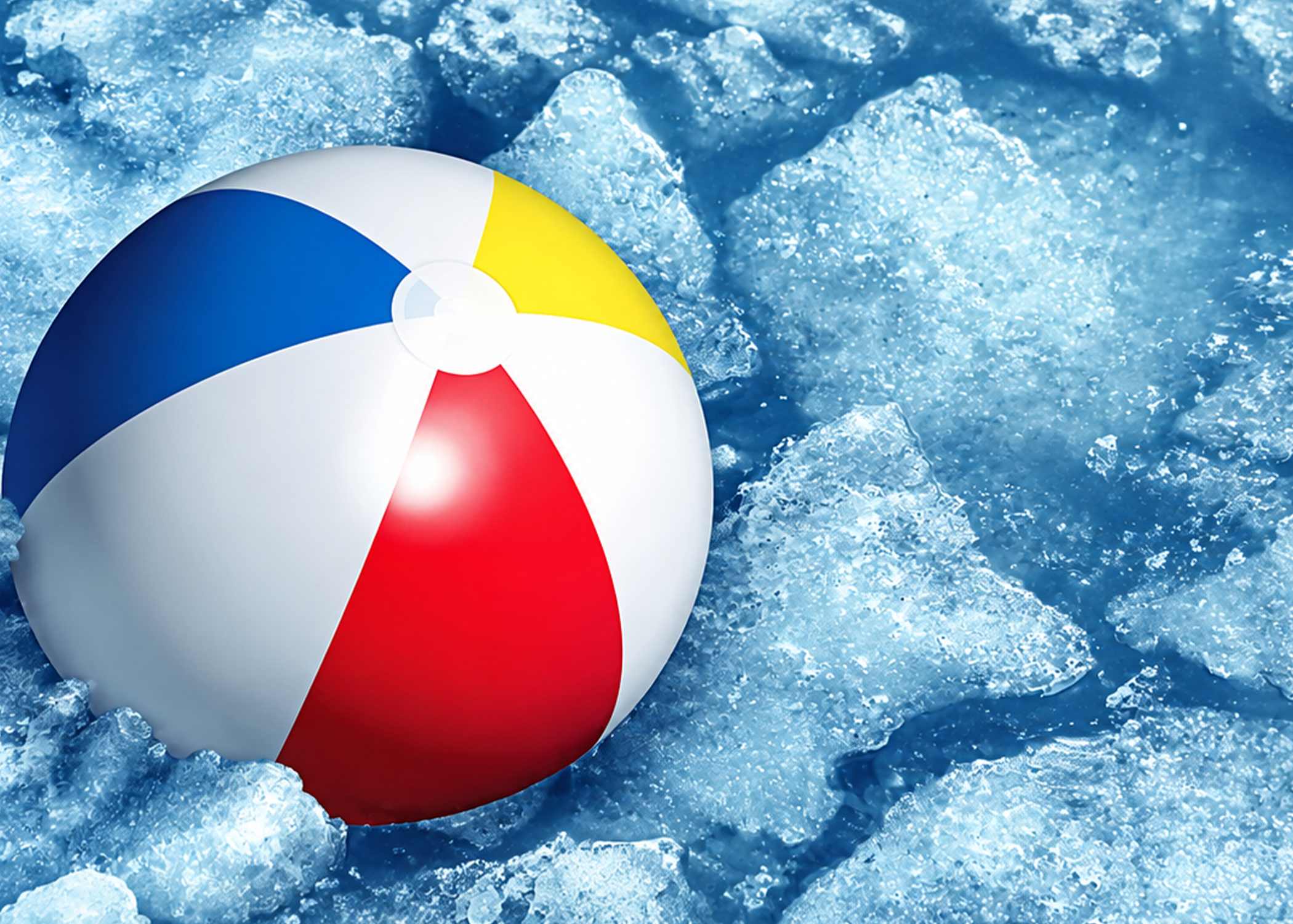 Colorful beach ball with red, white, blue, and yellow panels resting on crushed ice