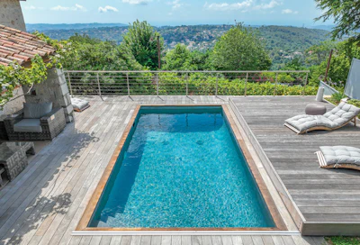 Luxury infinity pool on wooden deck overlooking forested hillside landscape with lounge chairs