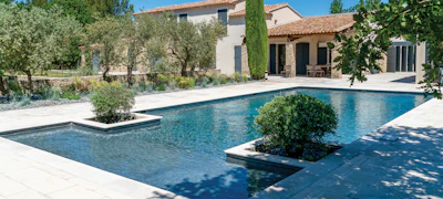 Luxury Mediterranean villa with infinity pool, manicured gardens, and stone terrace overlooking countryside estate