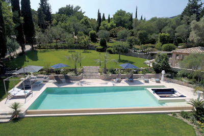 Luxury resort pool overlooking manicured gardens and cypress trees in Mediterranean landscape