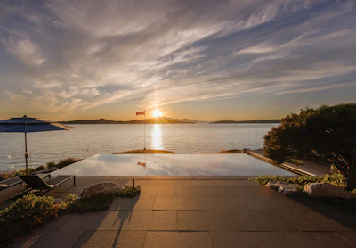 Sunset over a coastal bay with infinity pool overlooking the water and distant islands
