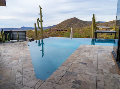 Luxury infinity pool with desert mountain views and saguaro cacti in Arizona landscape