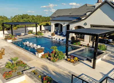 Luxury backyard with resort-style pool, black pergolas, white Mediterranean-style home, and manicured landscaping