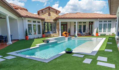 Luxury home courtyard with resort-style pool, manicured lawn, and Mediterranean architecture
